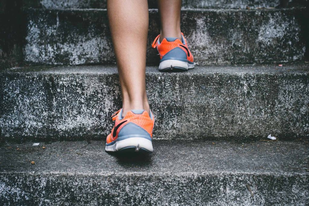 Person's legs and orange running shoes climbing stairs.