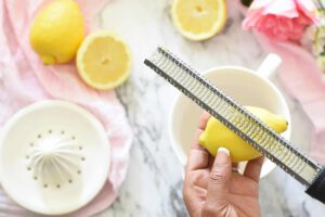 Woman zesting lemon with microplane zester over bowl