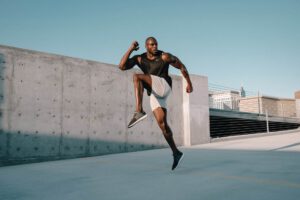 Muscular man performing a high knee exercise outdoors
