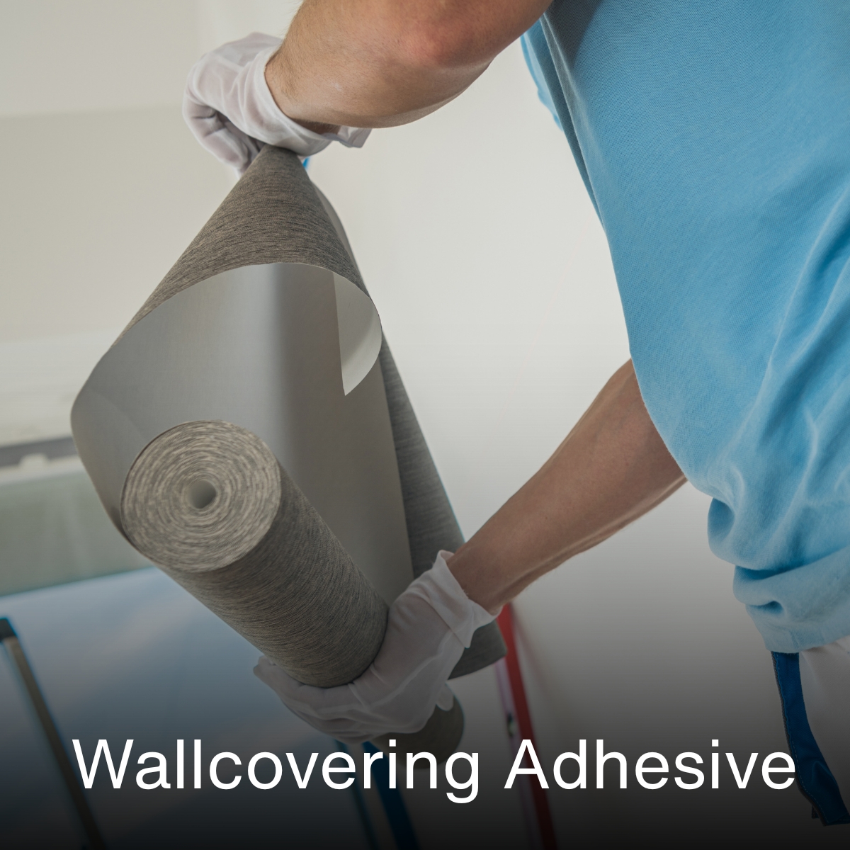 Close-up of hands applying wallcovering adhesive to wallpaper roll.