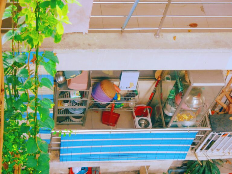 Overhead view of a balcony with plants, storage shelves, and various household items.